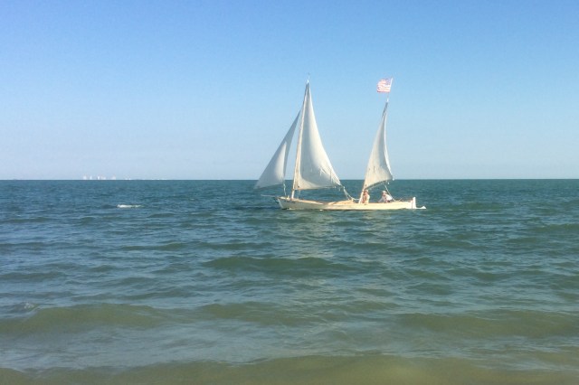 Interesting open boat sails close to the island shore.