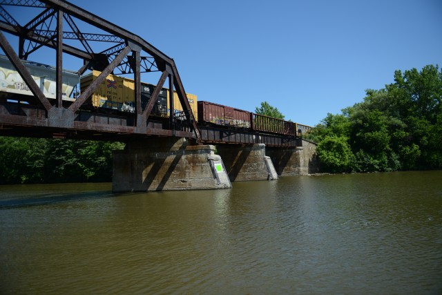 A train crosses over the bridge as we pass under it.  