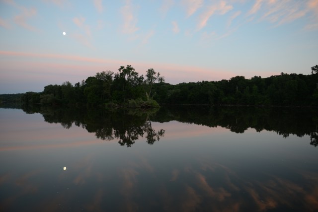 The moon rose against the  backdrop of twilight.